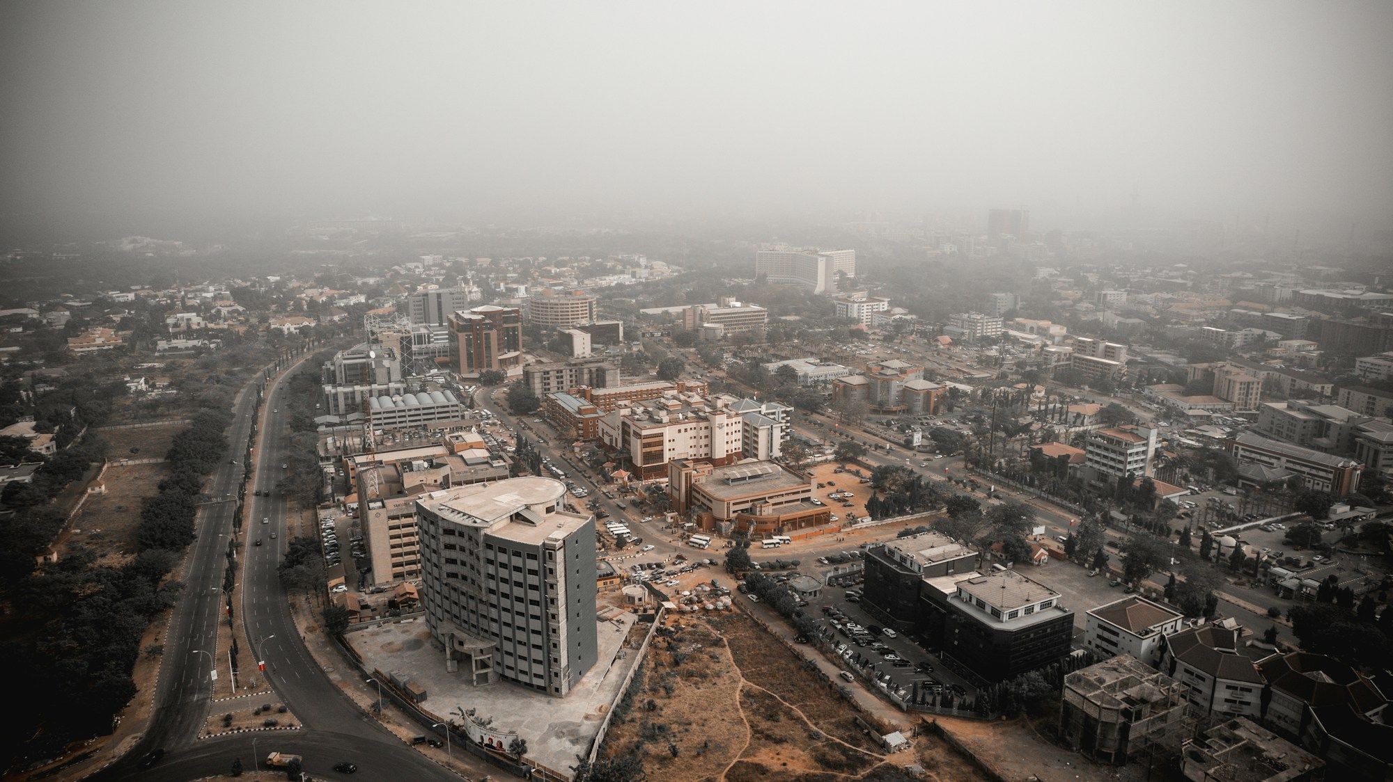 An aerial view of Abuja with roads and buildings partly covered by morning fog.